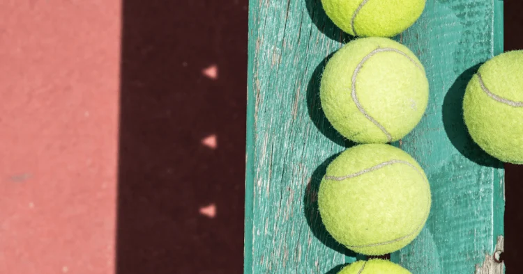 tennis balls on a tennis court sitting on bench