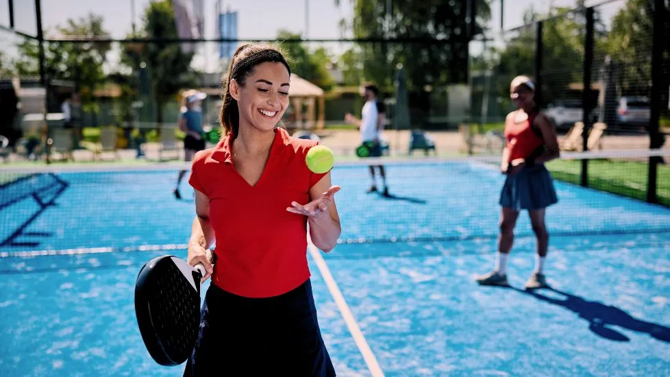 happy female on a padel court holding a πάντελ racket