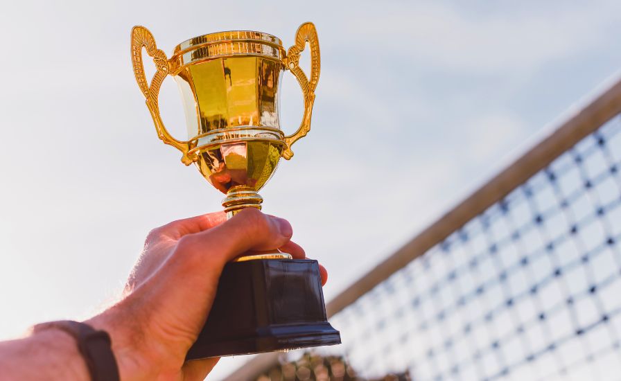 male tennis player holding a trophy after becoming a champion