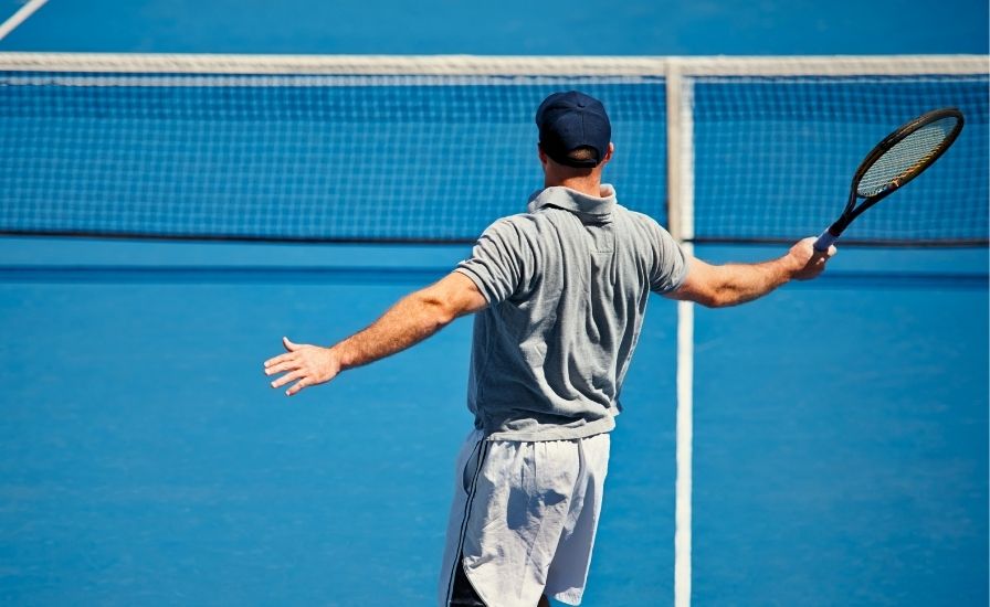 male tennis player hitting a one-handed backhand on a tennis court