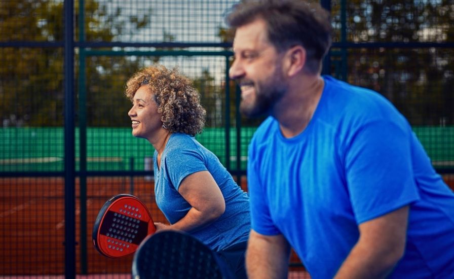 side view portrait of a mixed adult couple playing padel tennis